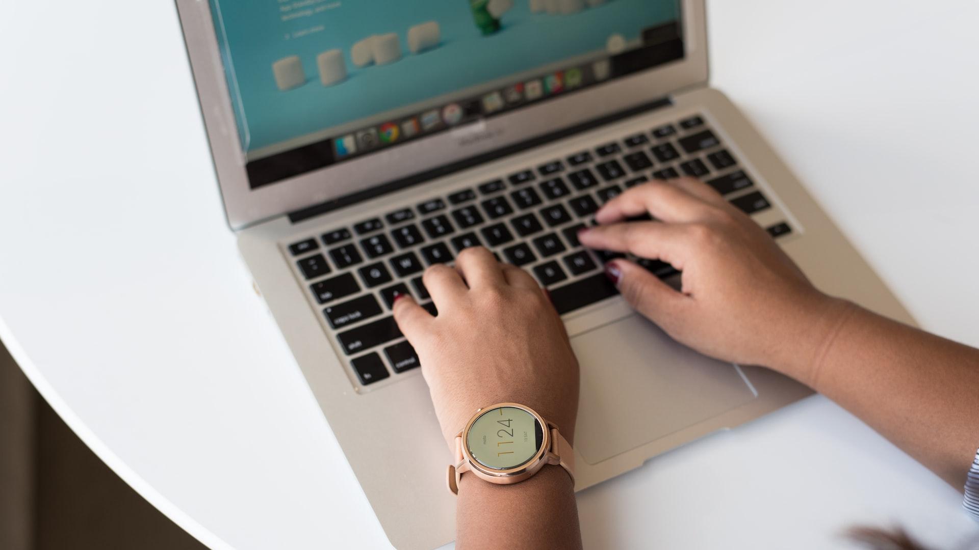 person using MacBook on white table